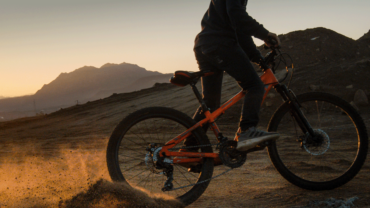A person riding a bike on a dirt track at sunset