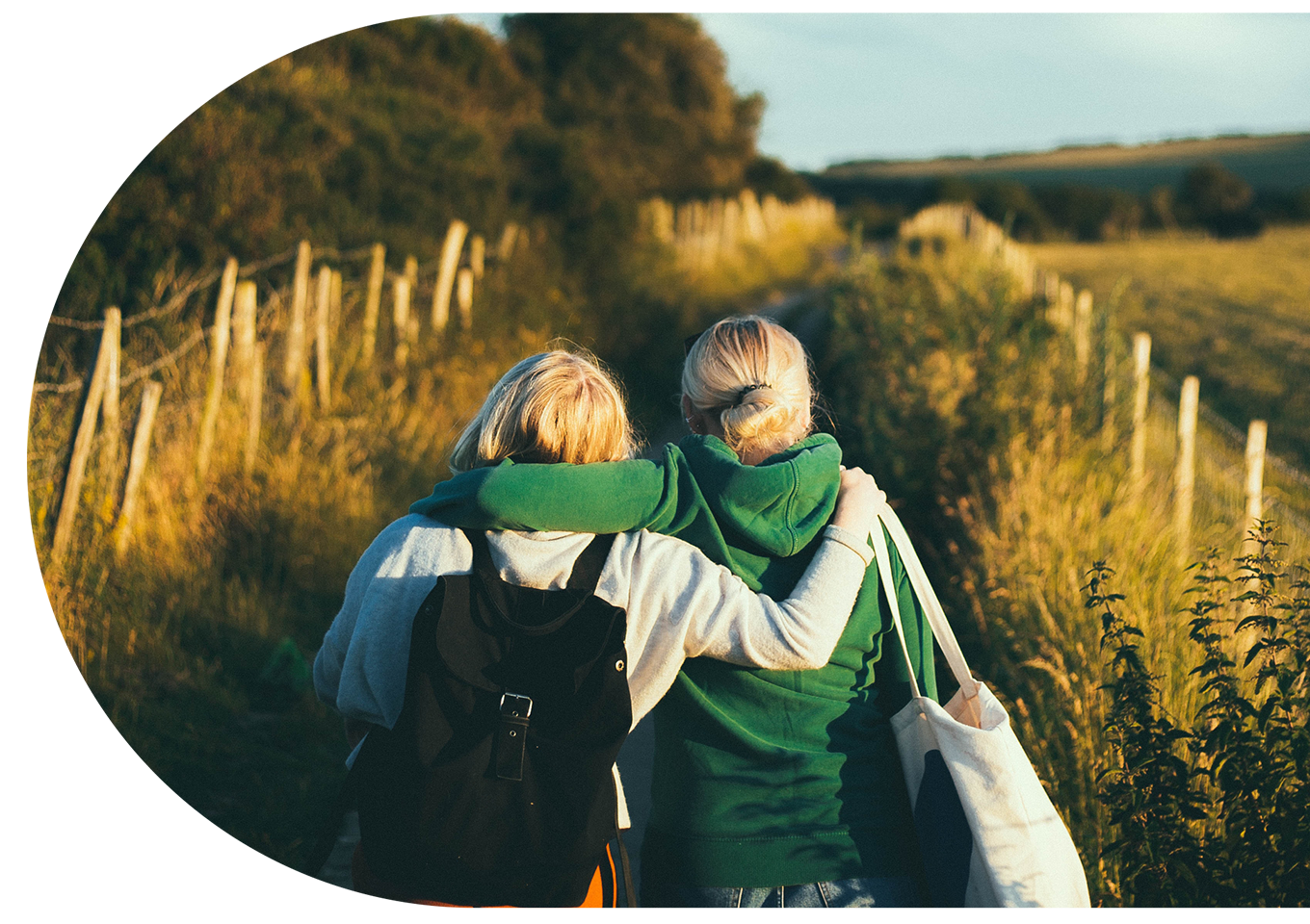 Two women walking arm in arm on a countryside trail