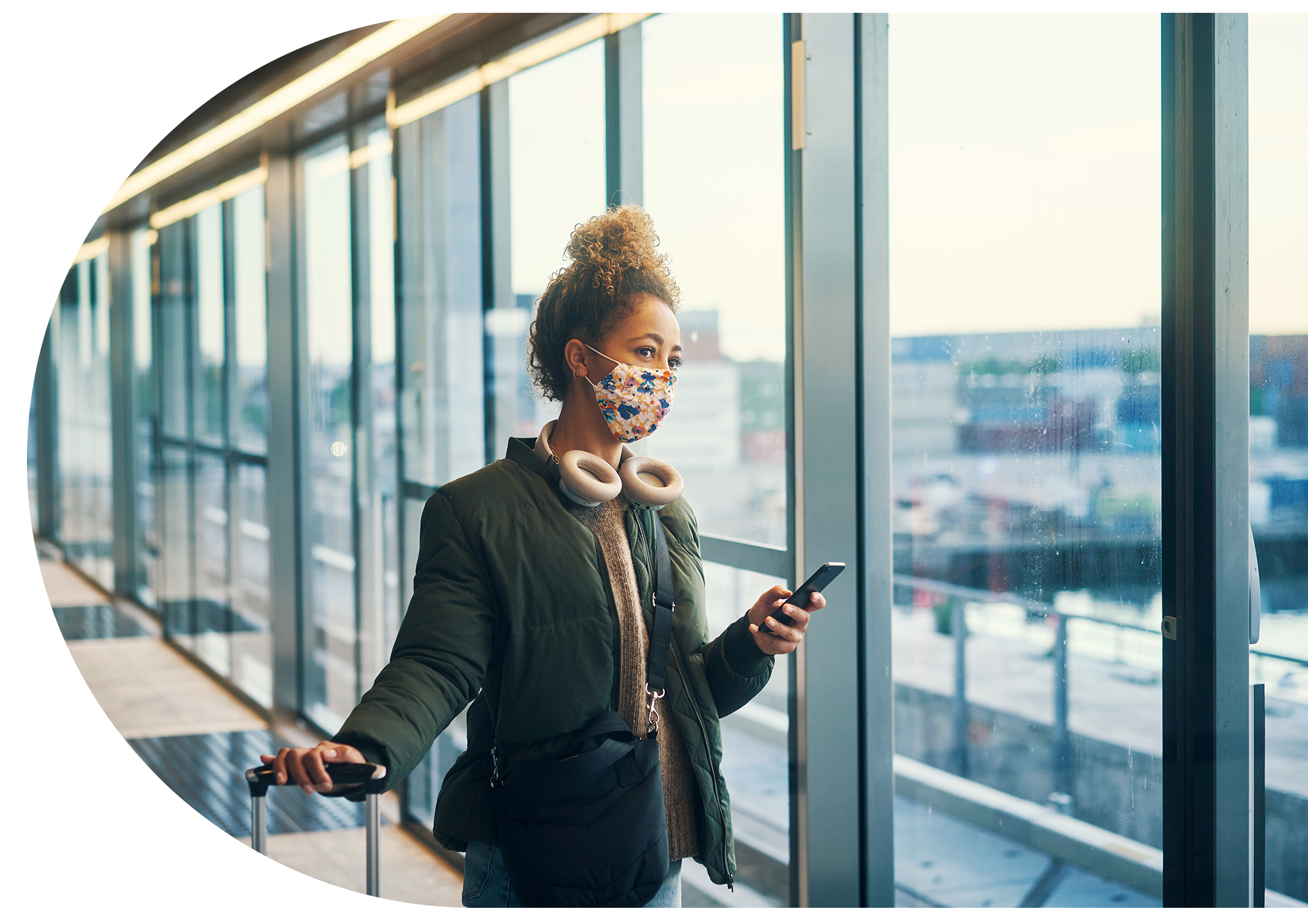 Woman with her phone in hand, looking out of an airport window