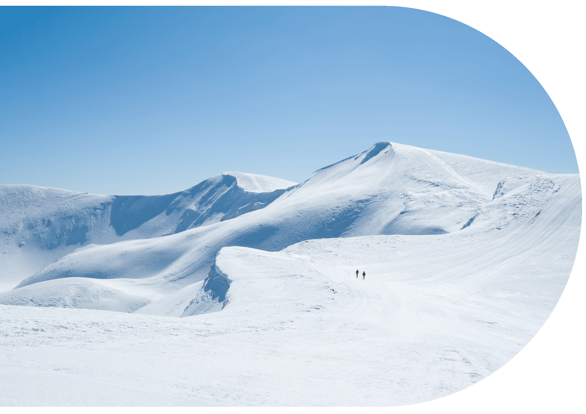 Two people hiking across a snow-covered mountain