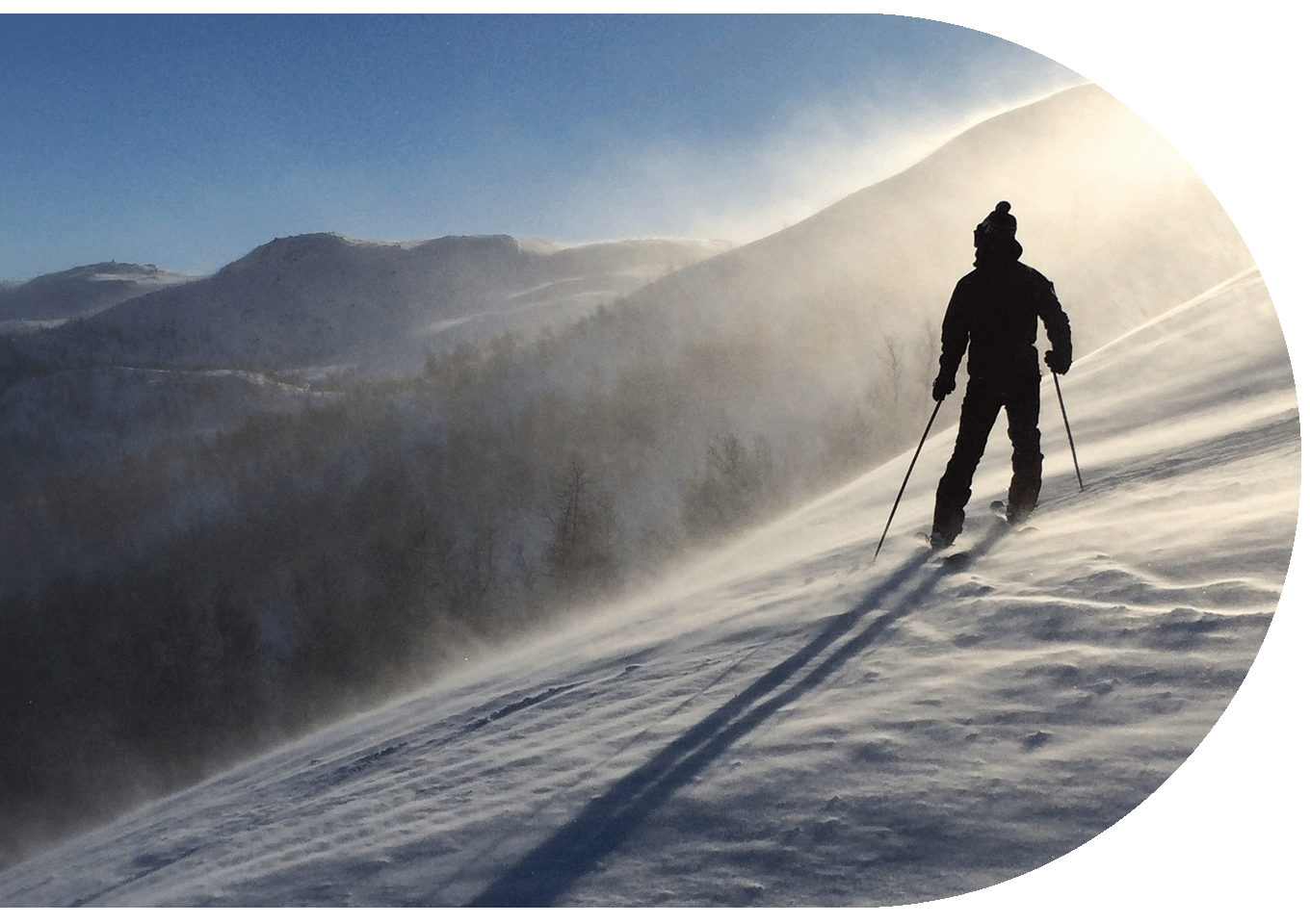 Skier standing atop a snowy mountain