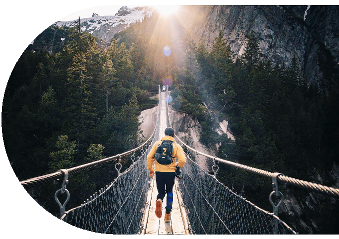 Long rope bridge connecting steep tree covered mountains