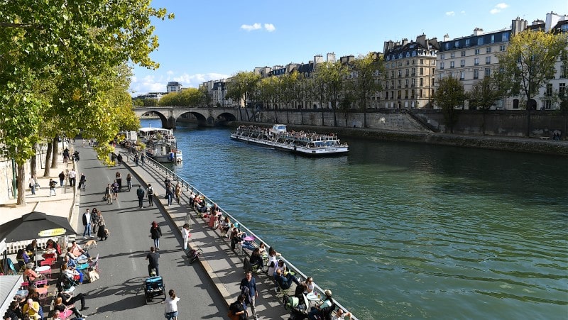 People sitting on the banks of the Seine river, Paris, France
