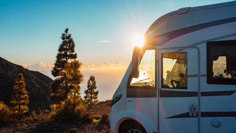Campervan parked on the edge of a mountain at sunset