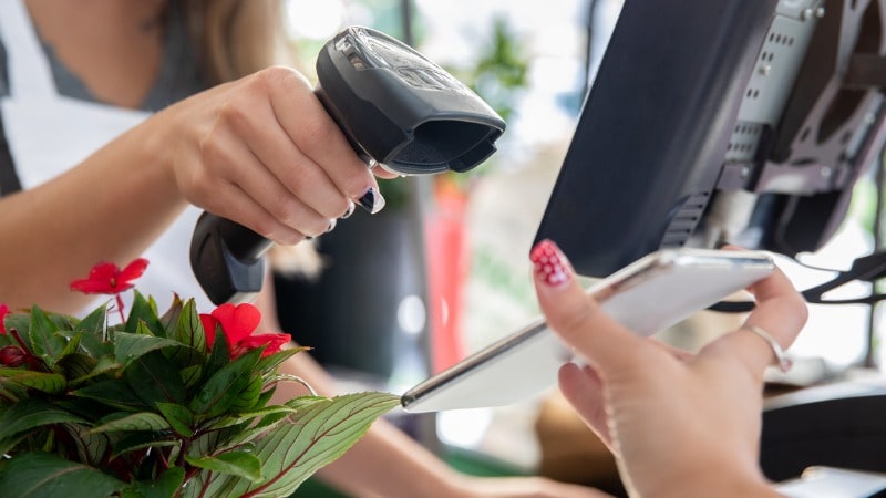 Shop worker scanning smartphone with scanning device